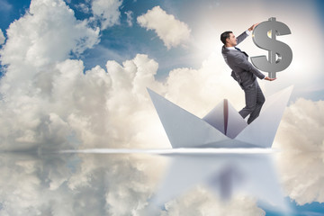 Obraz premium Businessman holding dollar riding paper ship boat