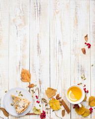Fototapeta na wymiar Autumn background with pumpkin pie, hot tea, yellowed leaves, book and rug. Perfect sunny autumn. A wooden light white autumn background for you. Copy Space. Place for text. Flat lay, top view