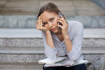 Tired businesswoman sitting with papers and phone