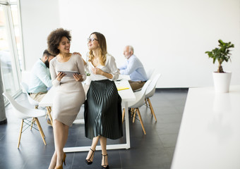 Two young businesswomen with a tablet in the office