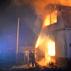 team fire fighter extinguish fire burning house at the night
