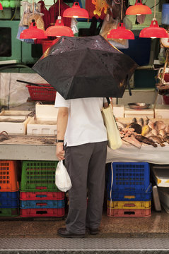Man holding an umbrella at a stall at Graham Street wet market, Hong Kong