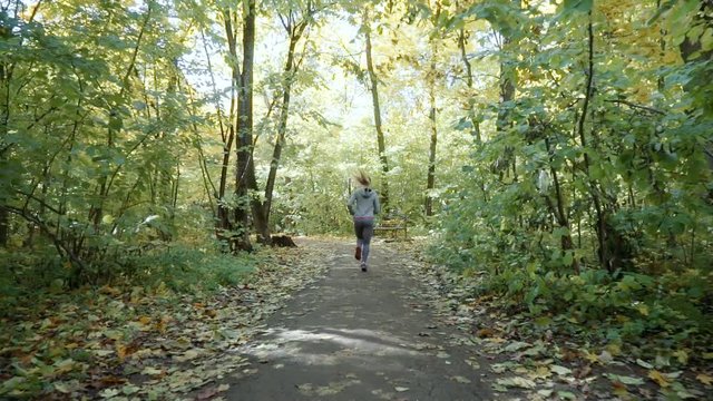 a girl runs in the park. the girl runs through the autumn park.