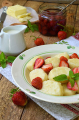 Sweet berry breakfast. Sweet lazy pierogi, dumplings with sour cream, butter and strawberry on wooden background. Italian gnocchi. Copy space for your text