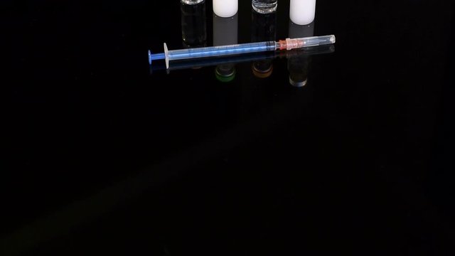 Four vial of insulin and disposable insulin syringe on black background, close-up. Set for diabetic.