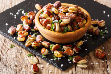 Tasty fried broad beans with salt and parsley close-up on a table. horizontal