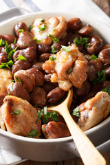 Hearty chicken baked with broad beans, garlic, onions and greens close-up. vertical