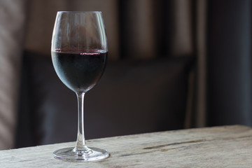Red wine in glass on brown wooden table.