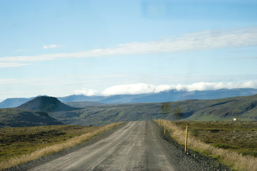 Road in a typical Icelandic landscape, a wild nature of rocks and shrubs, rivers and lakes.