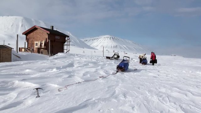 People on base of sled dogs husky Eskimo road of North Pole in Arctic. Way from airport Longyear to Pyramid Spitsbergen on background of glacier mountains Svalbard in Norway.