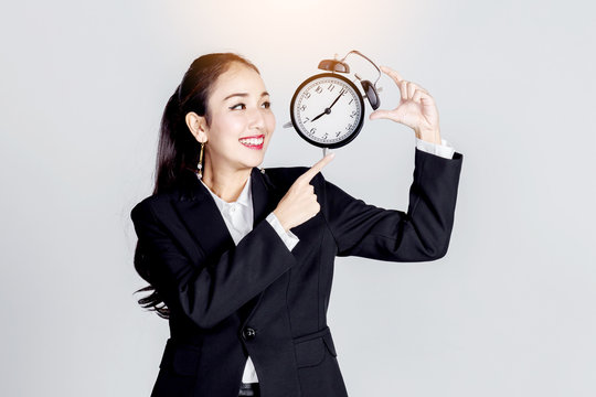 asian business woman smile and point finget to black retro alarm clock isolate white background