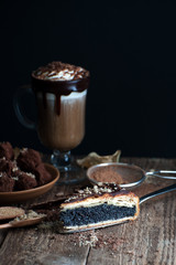 A piece of poppy pie and krfe in a tall glass on an old plank table..