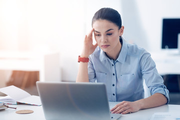 Tired female employee working on laptop at office