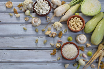 White vegetables and fruits on a wooden background - currant, cauliflower, champignons, radish, parsley, mushrooms, garlic. Onion, cabbage, mulberry, rice cashew beans Vegetarian food Flat lay
