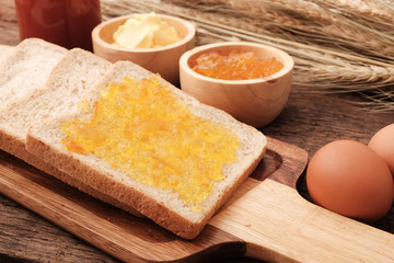 Slice whole wheat bread, butter and orange jam.