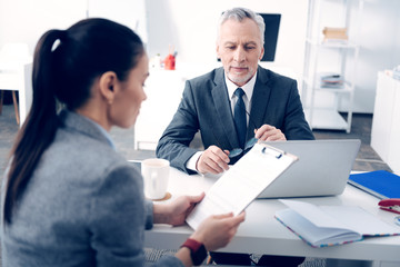 Friendly looking entrepreneur listening to young employee at office