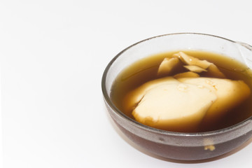Soft bean curd in hot ginger syrup in transparent bowl