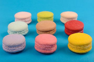 Fototapeta na wymiar French macaroons in rows with light blue background