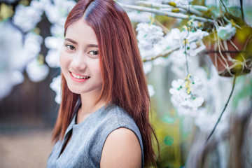 Fototapeta premium beautiful asian girl happy and relax pose in green garden with white flower fashion pose concept
