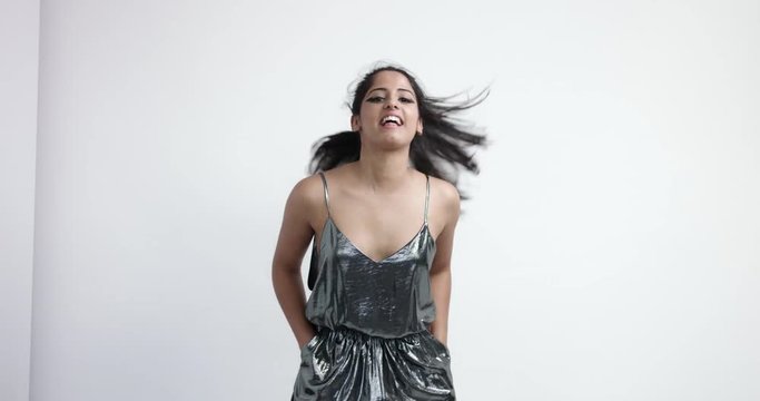 Young energetic Indian girl in a retro-futuristic metallic one-piece suit dancing and rocking and having fun