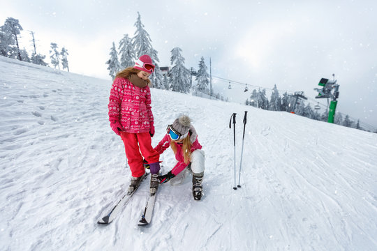 Skiing, winter fun-Mother preparing for skiing daughter