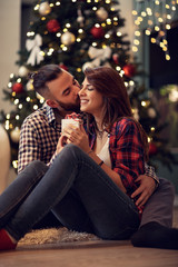Obraz na płótnie Canvas Husband hug and kisses his wife while gives her Christmas present