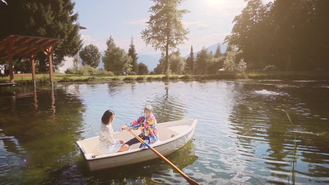 Mother and daughter paddling on boat in a beautiful lake. Slow motion