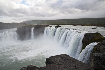 Wonderful view of Gadafoss Falls in a typical Icelandic landscape, a wild nature of rocks and shrubs, rivers and lakes.