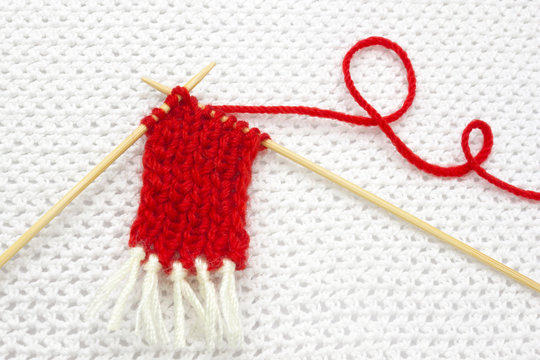 The Beginning Of Red Wool Scarf On The White Crochet Background