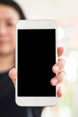Mock up mobile phone showing blank black smartphone screen display mockup with clipping path in business woman hand with bokeh light illumination in coffee shop or shopping mall