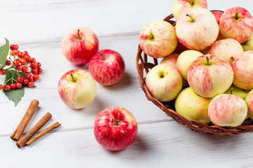 autumn mood composition with red apples in wicker basket and yellow leaves