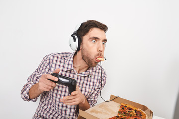 Adult silly bearded man with short dark hair in headphones, playing online games on personal...