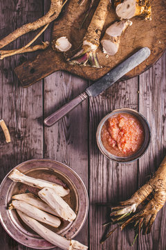 Horseradish roots and sauce on table, top view