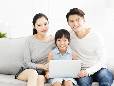 Happy asian family with laptop on sofa