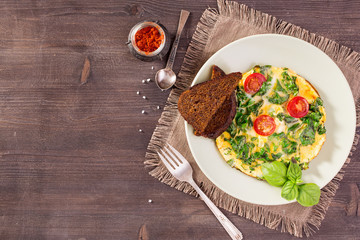 Scrambled eggs with kale and toast on wooden table. Top view with copy space