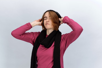Studio portrait on white background of a young attractive woman dressed in a winter sweater scarf and hat winking and looking at camera concept of winter clothing