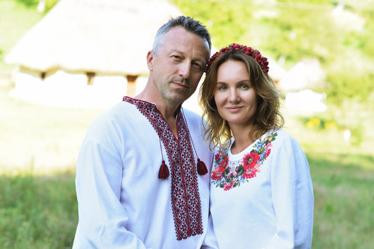 Ukrainian couple in traditional clothing vyshyvanka over landscape of tipical ucrainian village, summer outdoor.