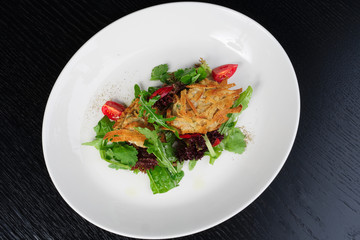 salad with chicken fillets on a white plate black background