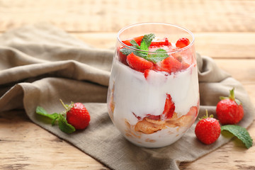 Glass of delicious strawberry dessert on wooden table