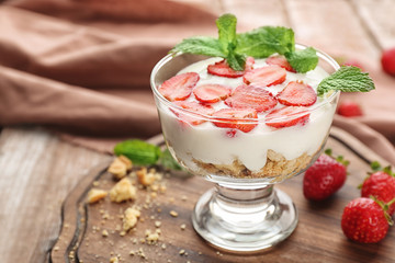 Glass of delicious strawberry dessert on wooden board