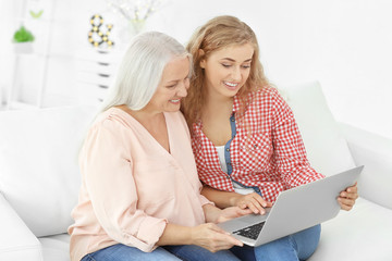 Young woman and her mother with laptop at home