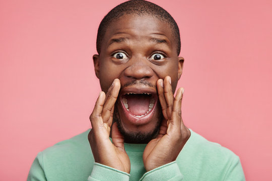Stunned overjoyed African American male student screams with excitement, keeps hands near mouth, being glad to enter university or college. Emotional happy surprised black man yells wow or omg