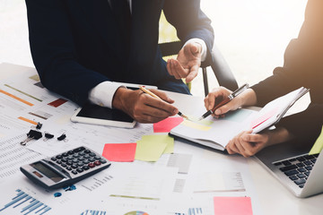 Close up of of business man and partners discussing documents and ideas at meeting with hand pointing on business graph paper. Vintage tone.