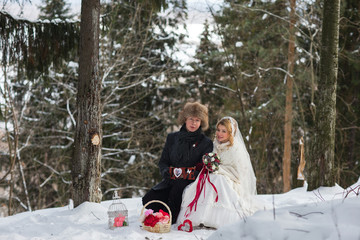 Stylish beautiful young couple bride and groom, dog sitting on the background of a winter landscape