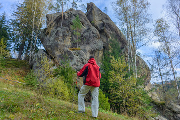 A man  a tourist in the mountains on hiking on the background of a rock.