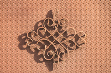 Forged decorative element with shadow on an iron background.