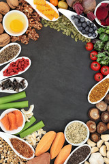 Brain boosting health food background border with fish, vegetables, seeds, nuts,   fruit, herbs and pollen grain on slate. Foods high in omega 3, vitamins, minerals, antioxidants and anthocyanins. 