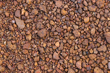 Surface of red rocks dirt and pebbles lay on the floor. It was crushed and cracked. Use for background or banner website and template.