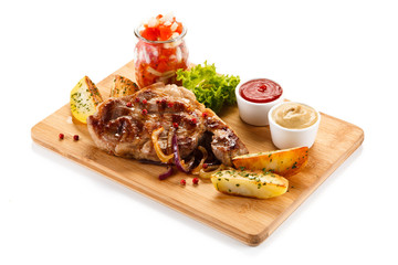 Grilled steak with potatoes on cutting board