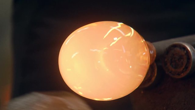 the red-hot glass is spinning on a stick